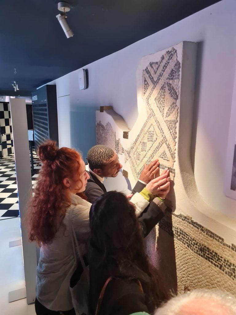 Una mediatrice della Girobussola guida i partecipanti nel toccare frammenti di un mosaico murario